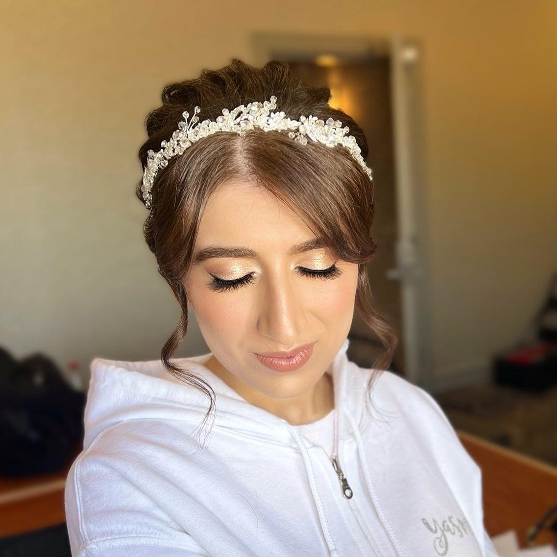 Bride with shimmer lids, soft brows, and an updo with a crystal headpiece, getting ready