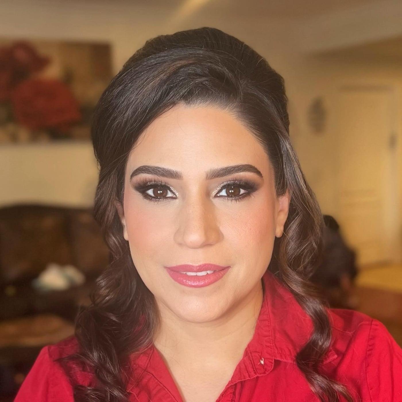 Client with a brown smoky eye, full lashes, and a pink lip in a red top