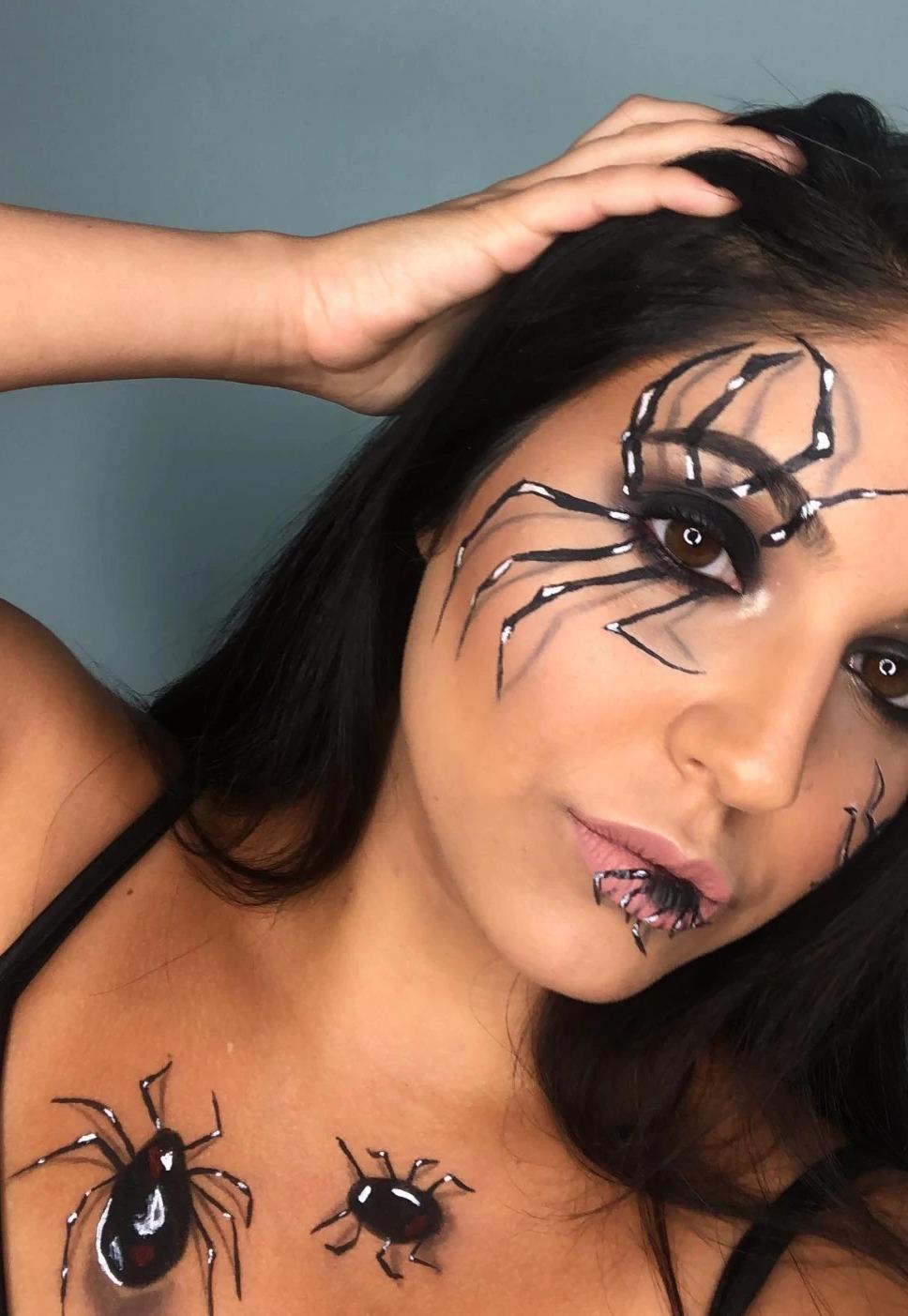 Spider Halloween makeup: long black spider legs painted around one eye, a small spider on the lower lip and two more painted on the chest