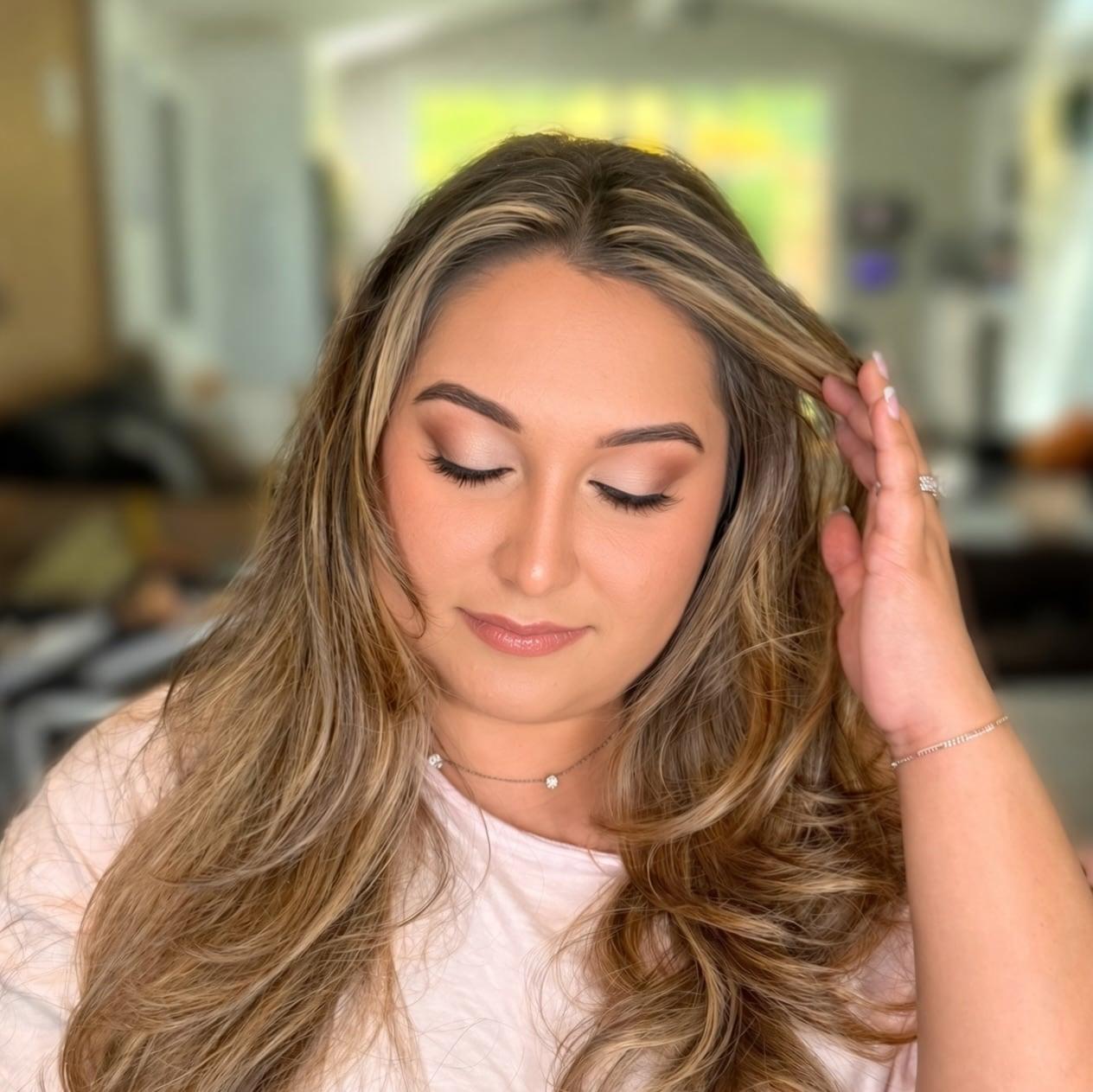 Client with bronze soft glam eyes and blonde waves, looking down