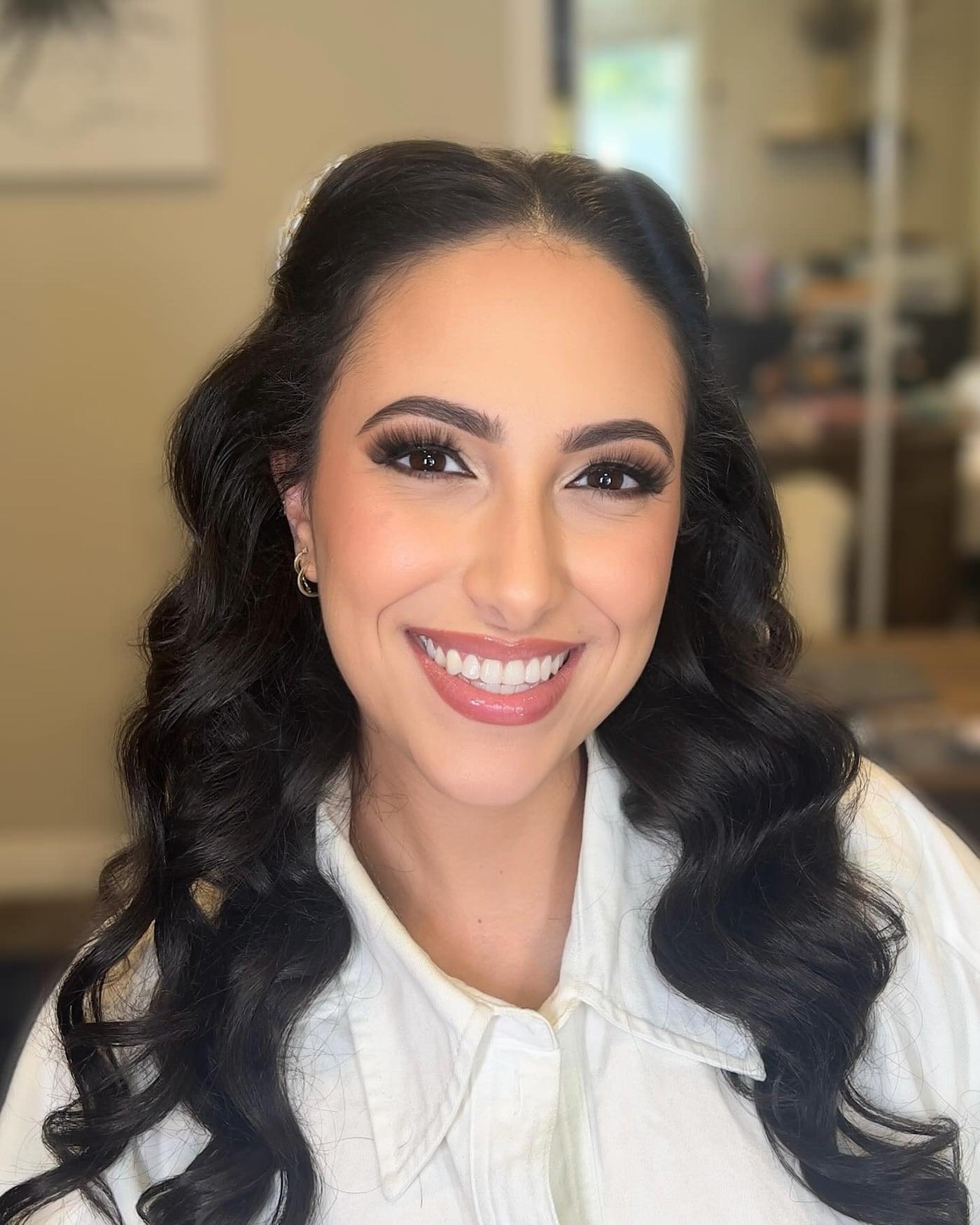 Smiling client with glam makeup and voluminous curls in a white shirt