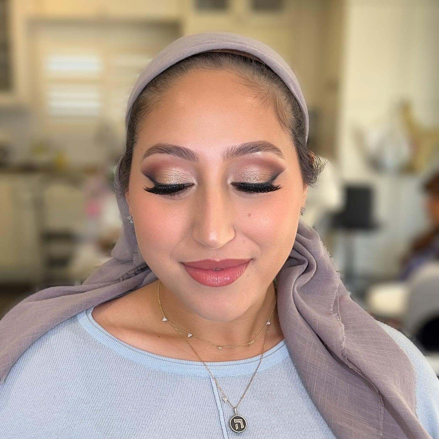 Client in a grey head wrap with shimmer lids, winged lashes, and a pink lip