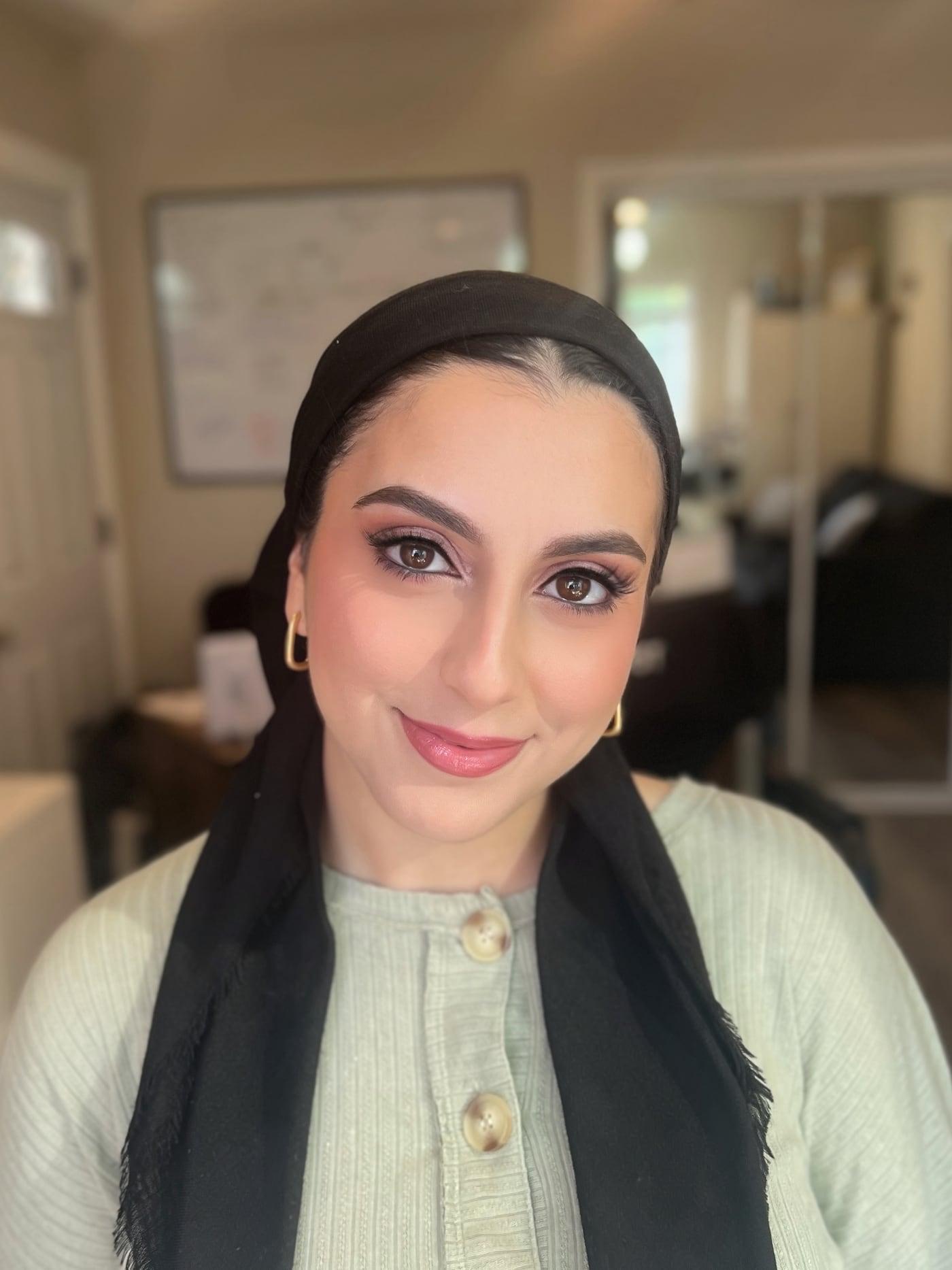 Smiling client in a black headscarf with soft glam eyes and a rosy lip