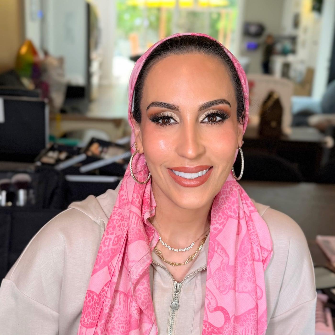 Smiling client in a pink scarf with bronze eyes, lashes, and glowing skin